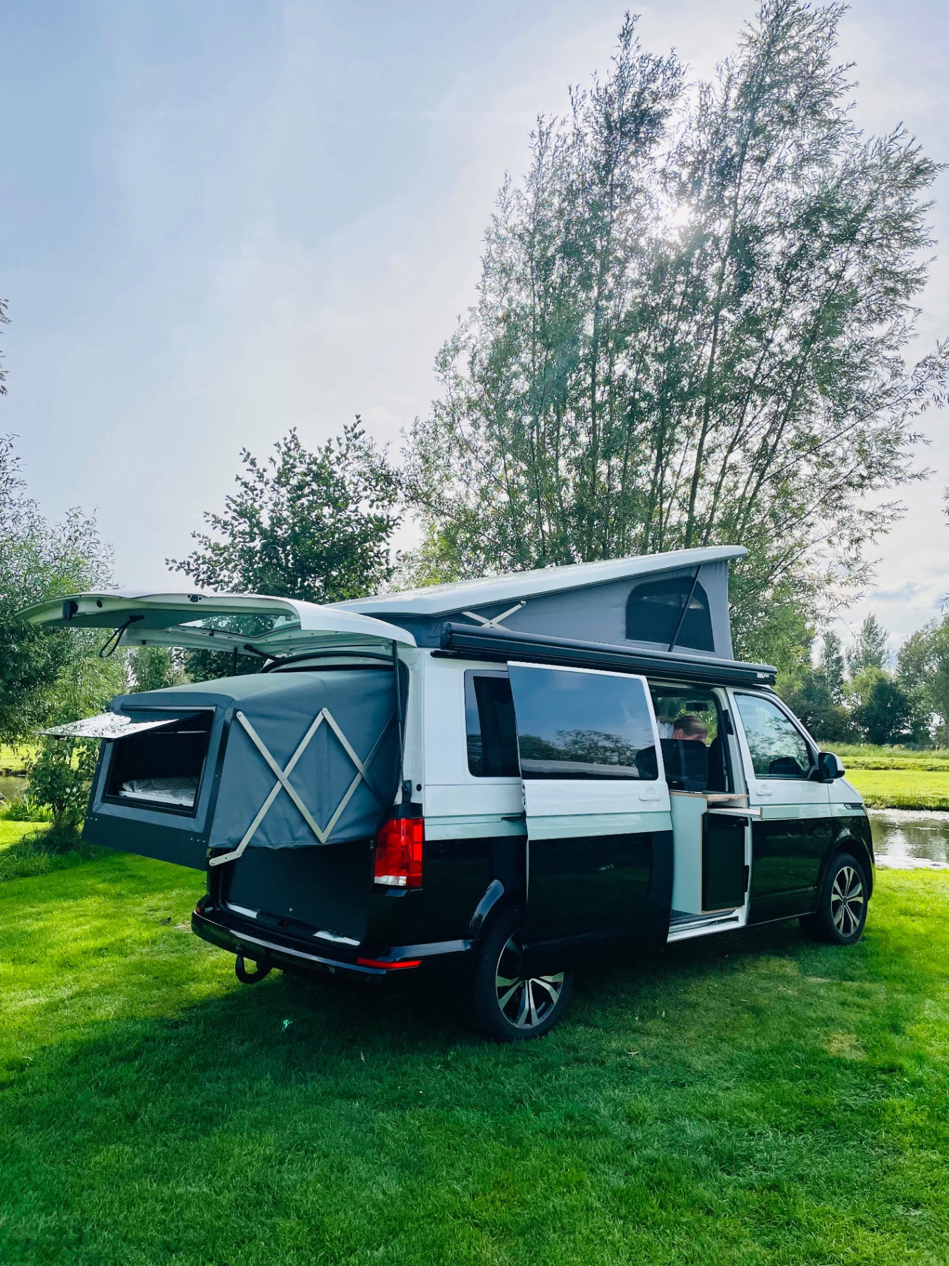 Zwei Wally-Van Camper auf einer Wiese mit Bergen im Hintergrund